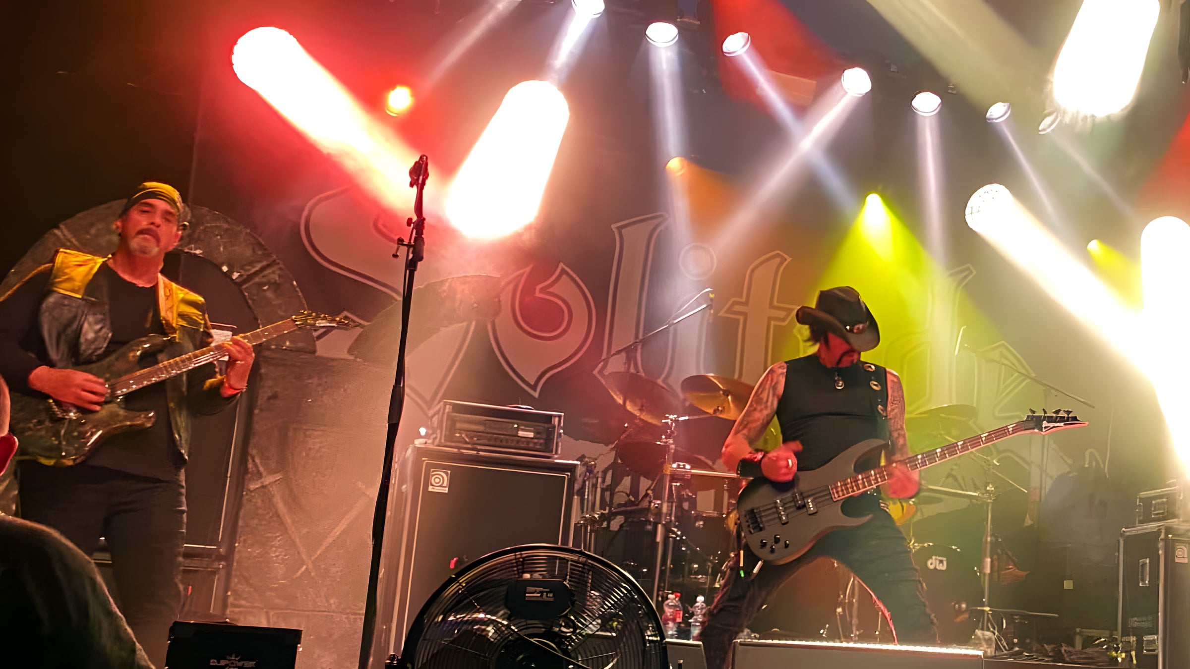 Edgar Rivera on guitar and Lyle Blackburn on bass in front of the Solitude Aeturnus backdrop, white and red spotlights cutting through the haze.