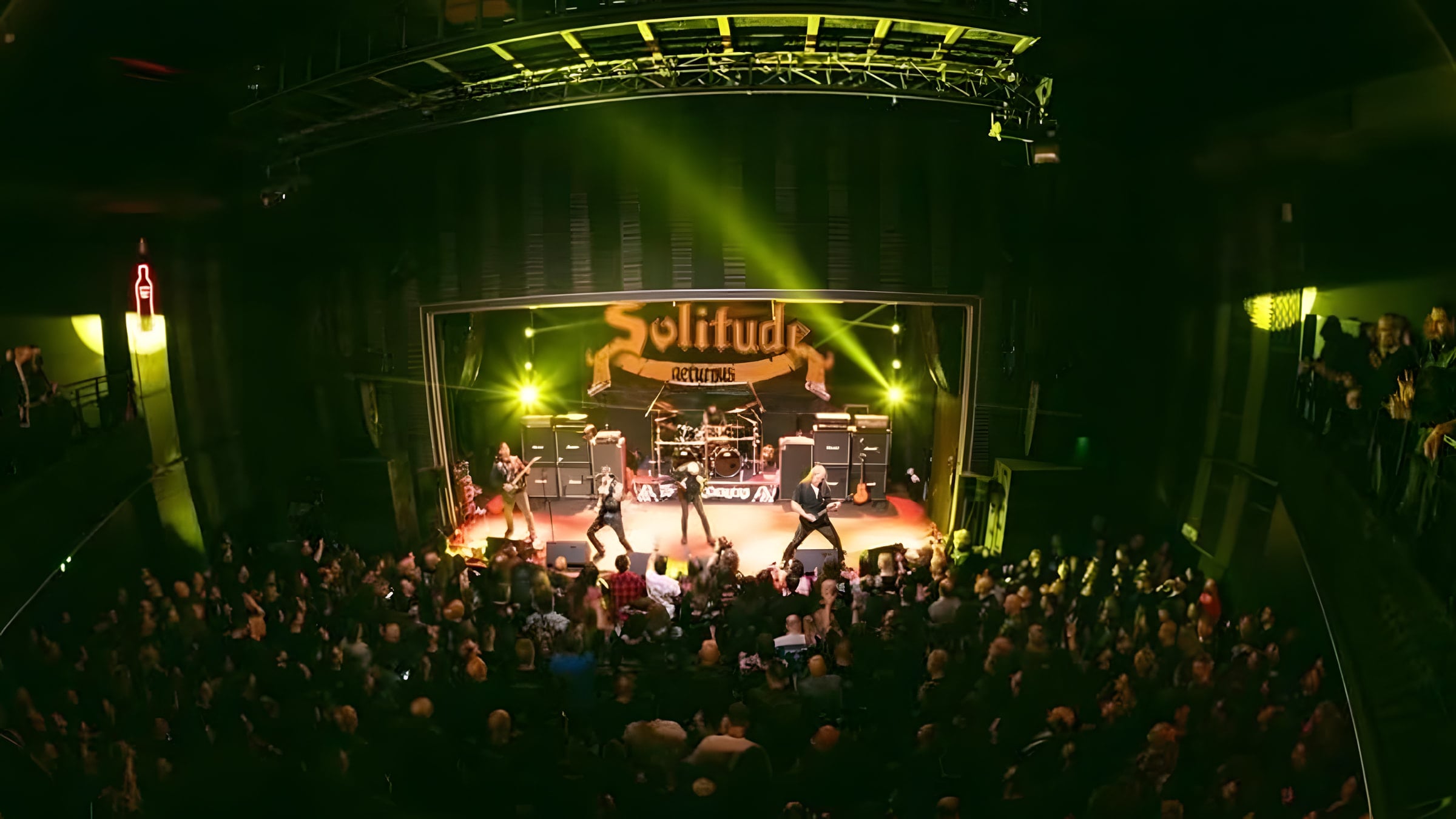 Solitude Aeturnus on stage under yellow light, seen from the balcony of a packed theatre, the band's banner hanging behind the drum riser.